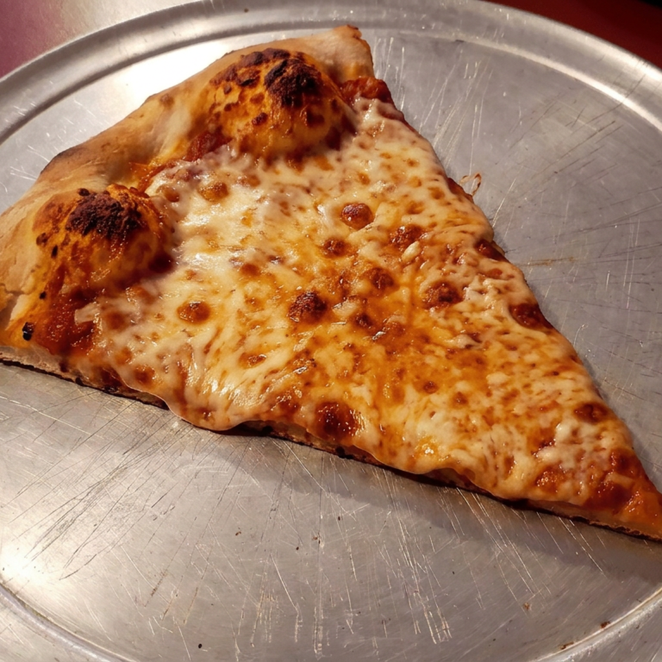 Large slice of cheese pizza with a golden-brown crust served on a scratched metal plate.